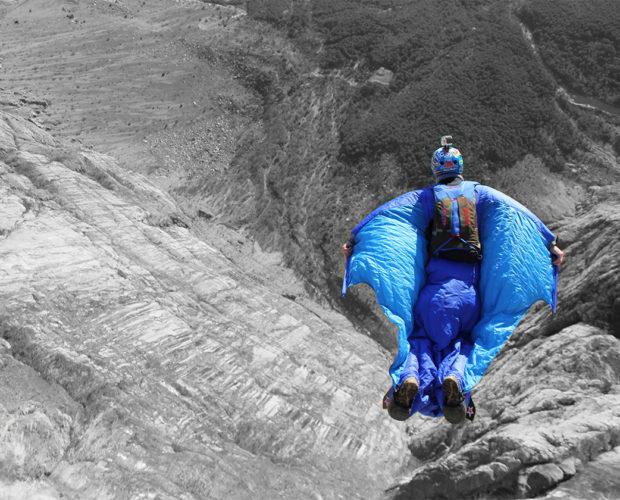Blue wingsuit flyer gliding over rocky canyon