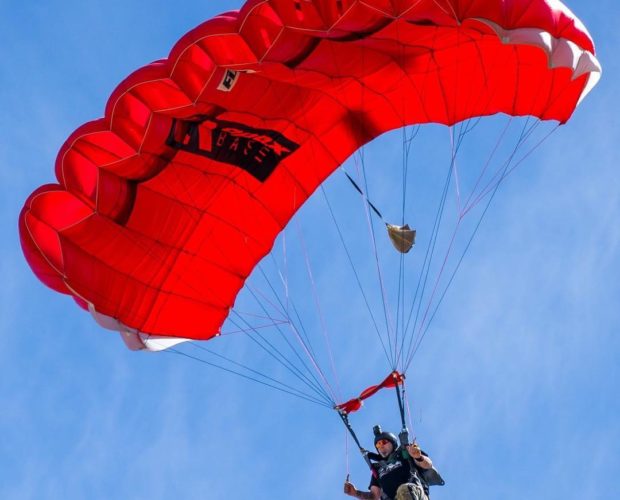 Skydiver with red parachute against blue sky