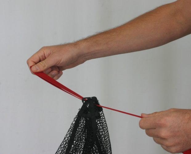 Hands tying red strap on black mesh net