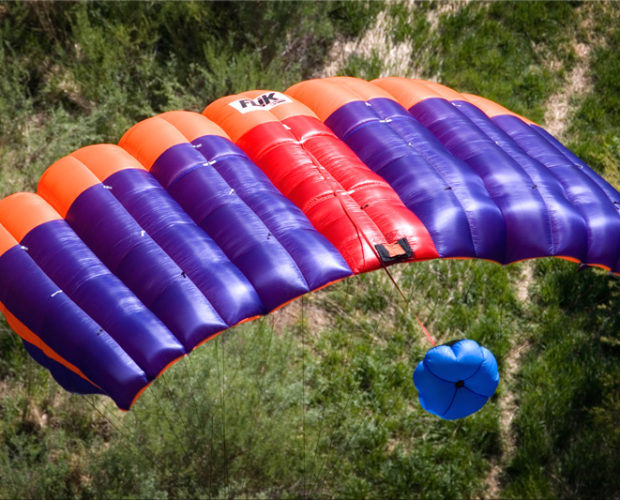 Colorful purple and orange parachute canopy over trees