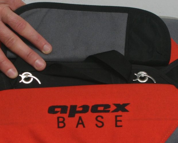 Hand holding red Apex Base travel bag