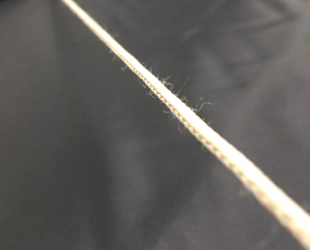 Hand holding frayed rope against black fabric